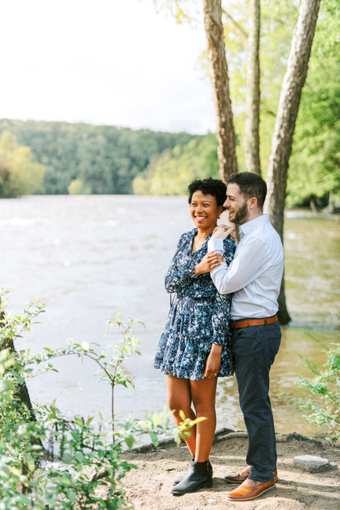 Couple laughs together on Chattahoochee river for a Chattahoochee Coffee Company engagement photography session