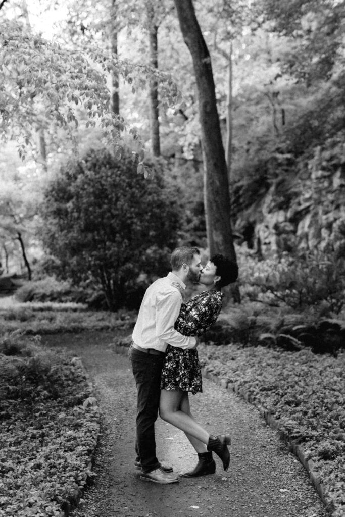 Couple kisses on a forest path during a Chattahoochee Coffee Company engagement photography session