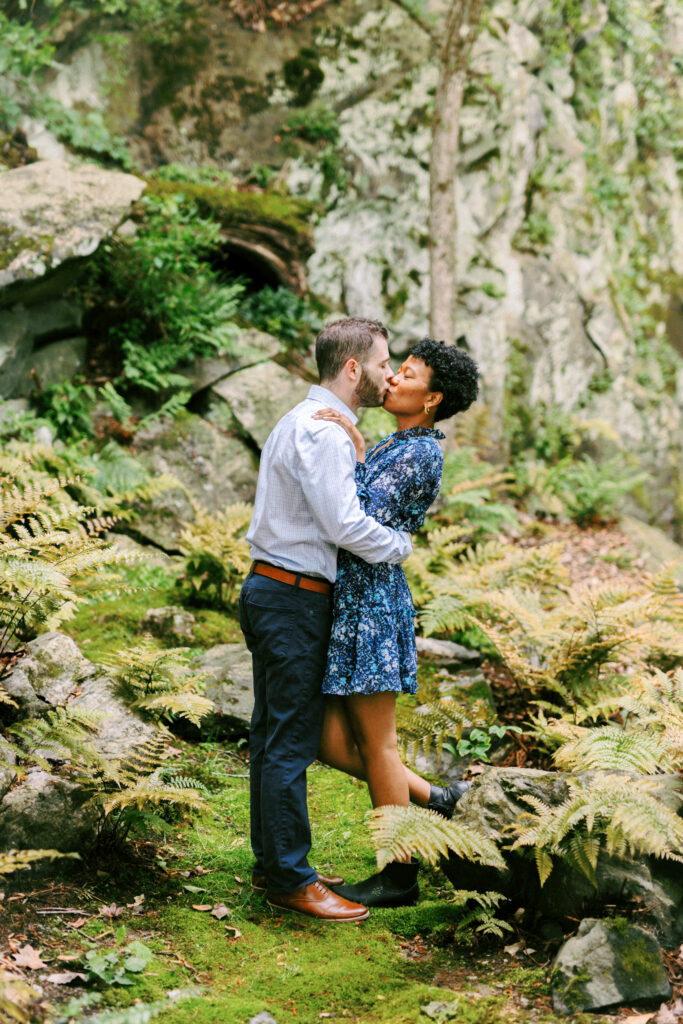 Couple kisses among the ferns at Chattahoochee Coffee Company in Atlanta, Georgia during engagement photo session