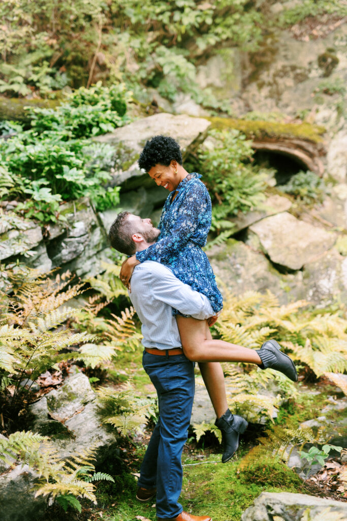 Couple dances among the ferns during engagement photo session at Chattahoochee Coffee Company in Atlanta, Georgia