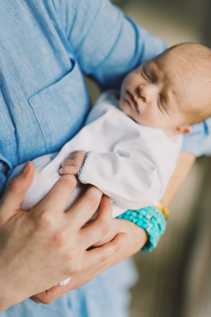 Newborn baby holding mom's finger