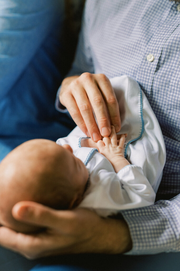 Father holding newborn baby hand