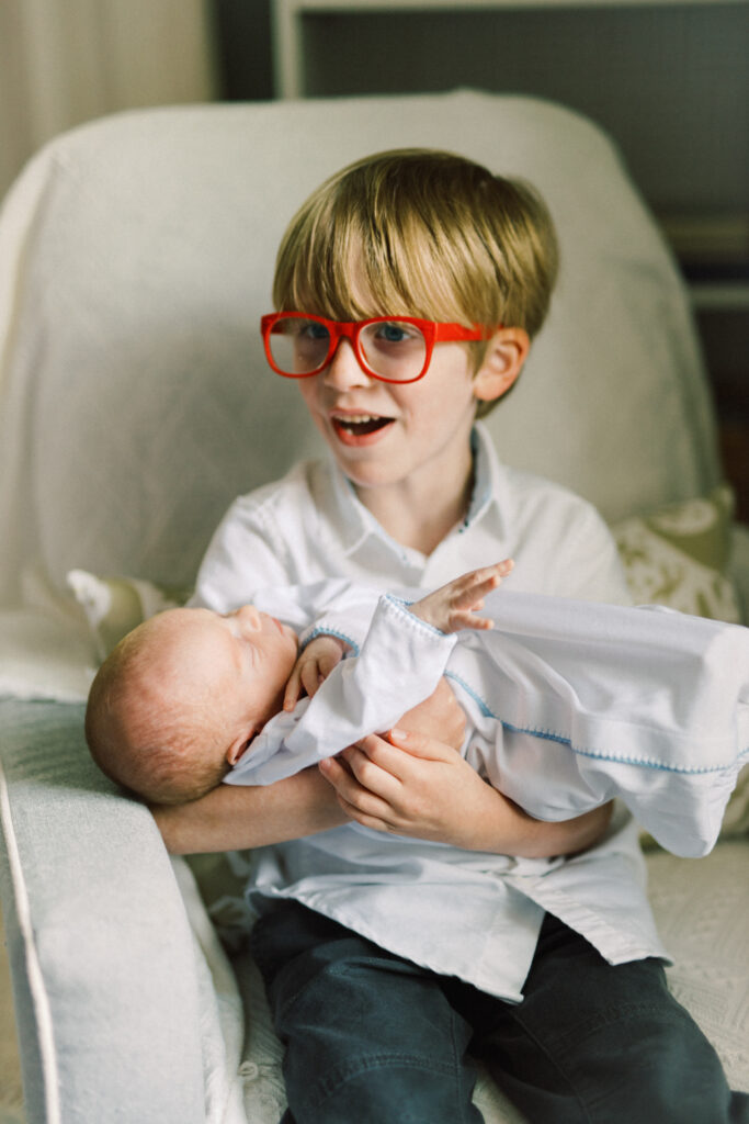 Big brother holding newborn baby brother