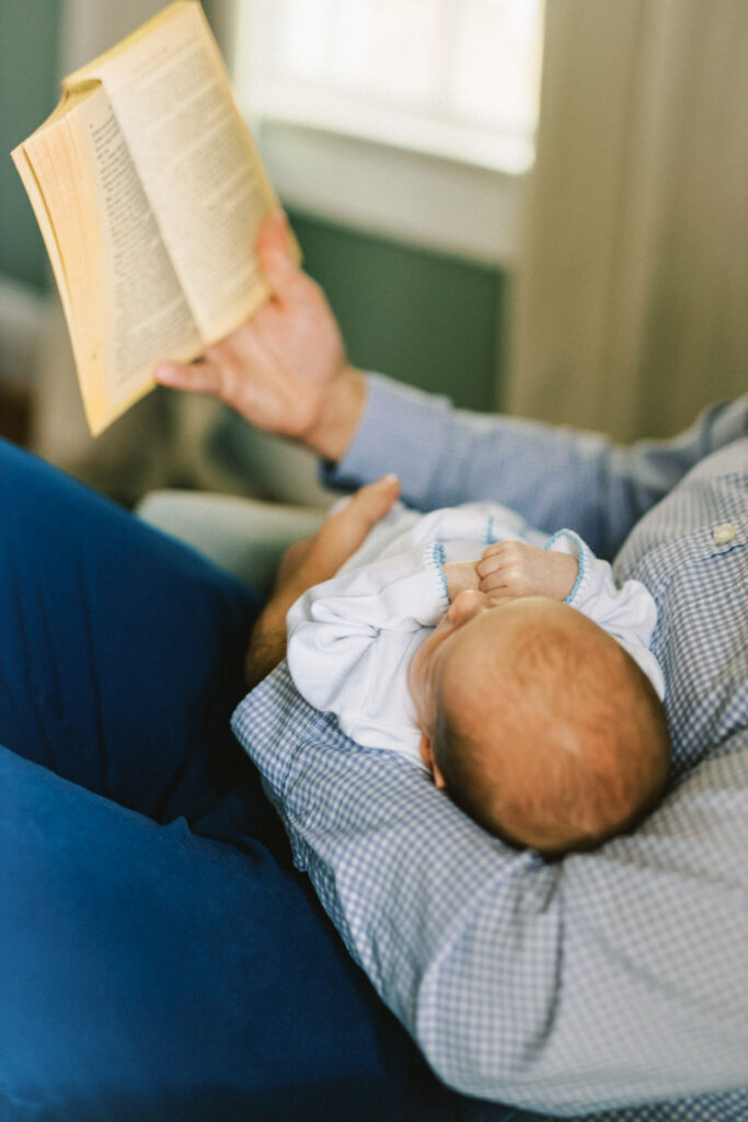 Father reading to sleeping newborn baby