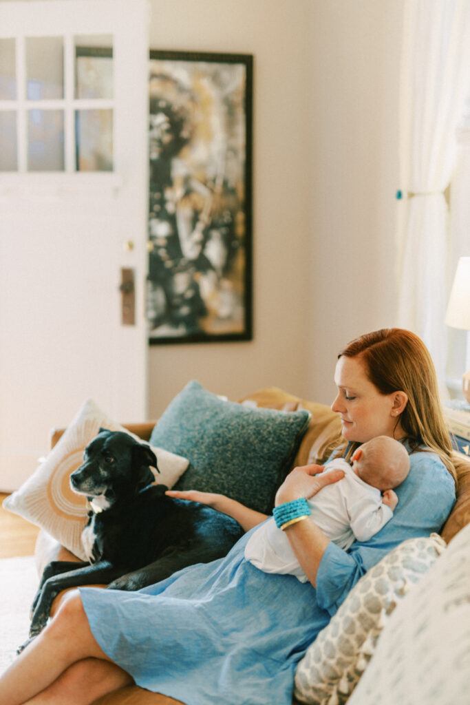 Newborn mother on couch with baby and devoted dog