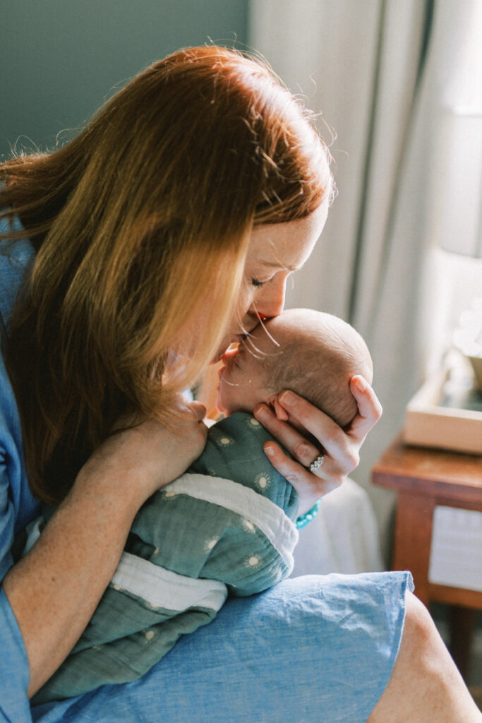 Mother sweetly kisses newborn baby in nursery