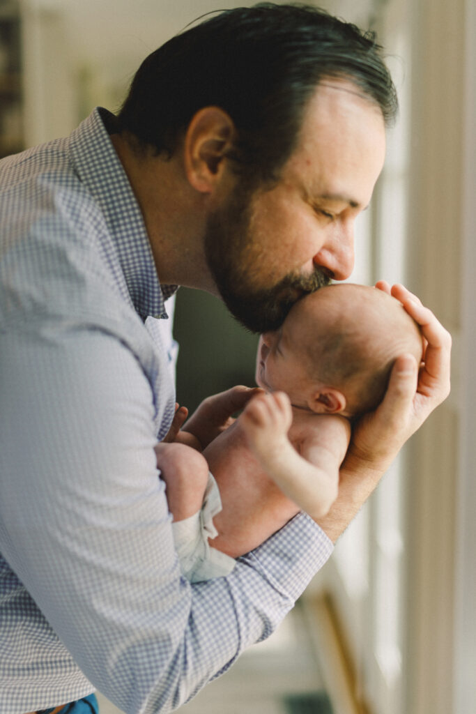 Newborn father kissing baby