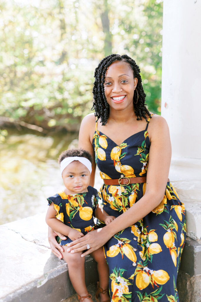 Mom and daughter smile in matching lemon outfits during family session at gazebo over Lake Clara Meer in Piedmont Park