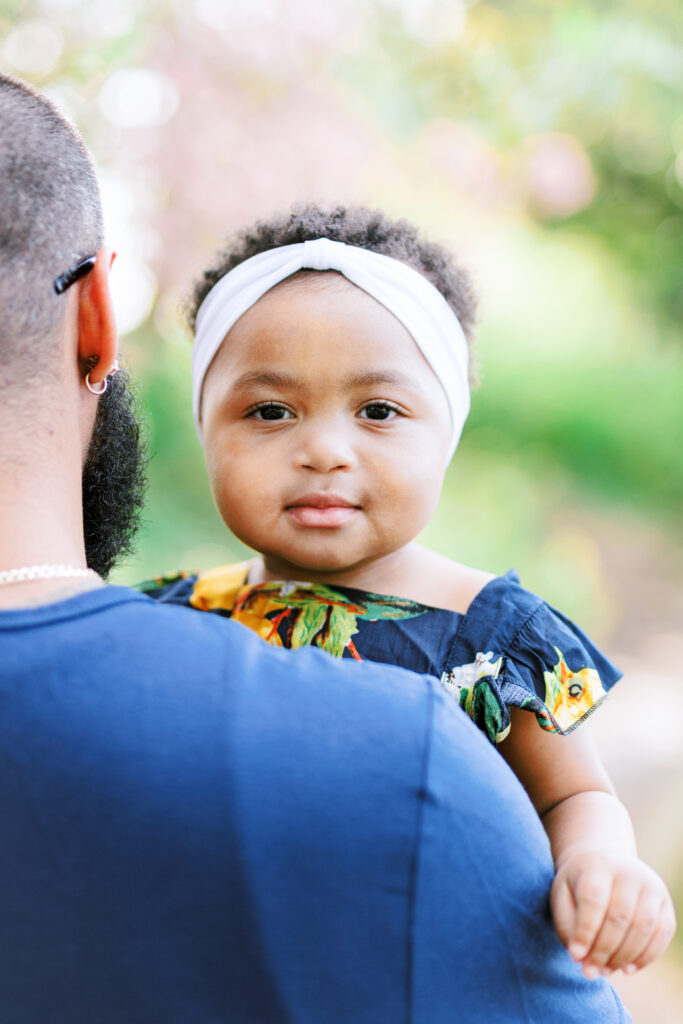 Beautiful baby girl smiles in the shade next to lake at Piedmont Park