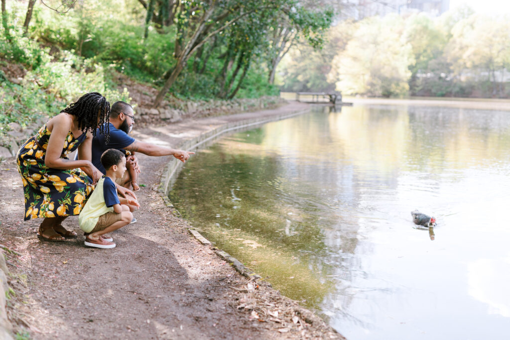 Family of 4 plays and looks at ducks while wearing matching lemon outfits in Piedmont Park, Atlanta