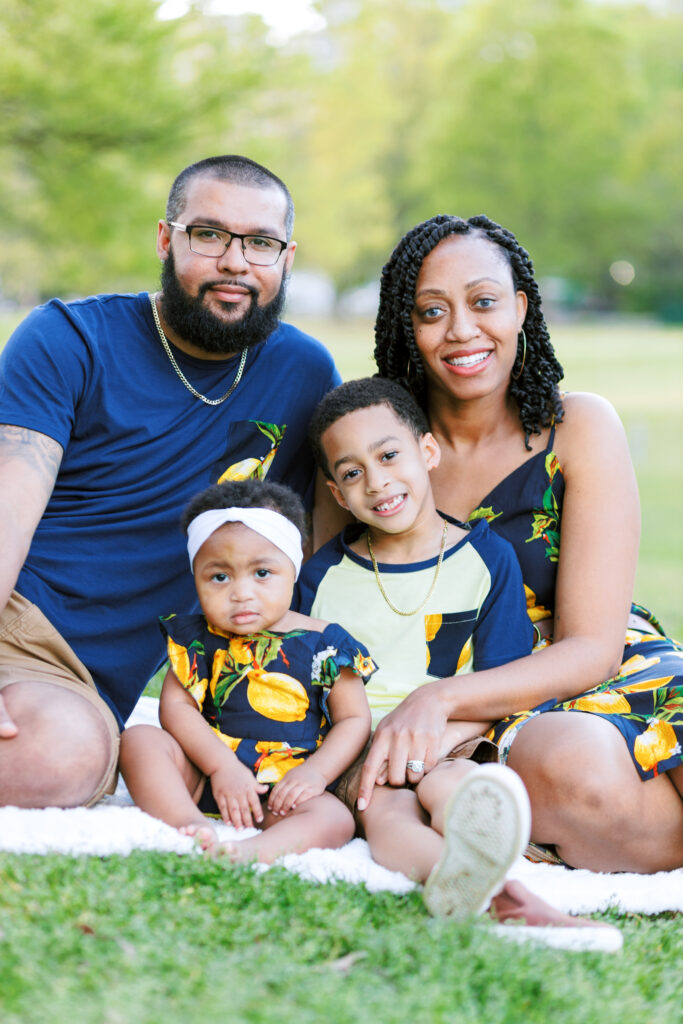 Family of four smiles in a field during summer family photo session