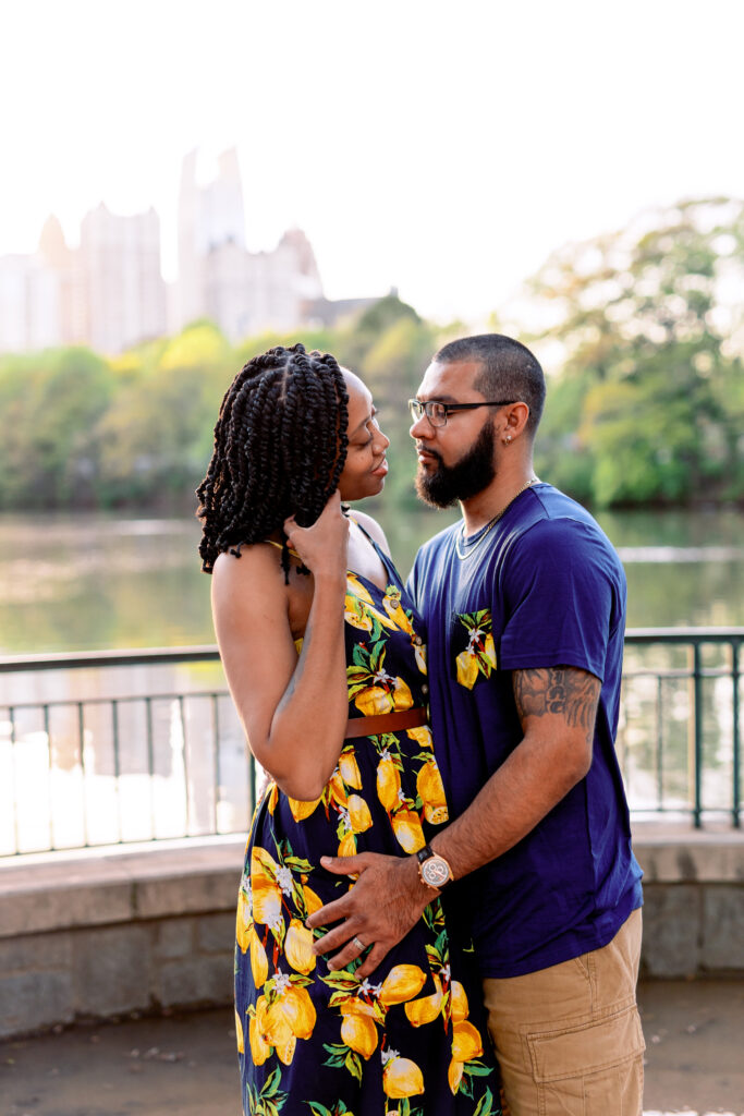 Couple smiles at each other at sunset in front of Atlanta Skyline at Piedmont Park