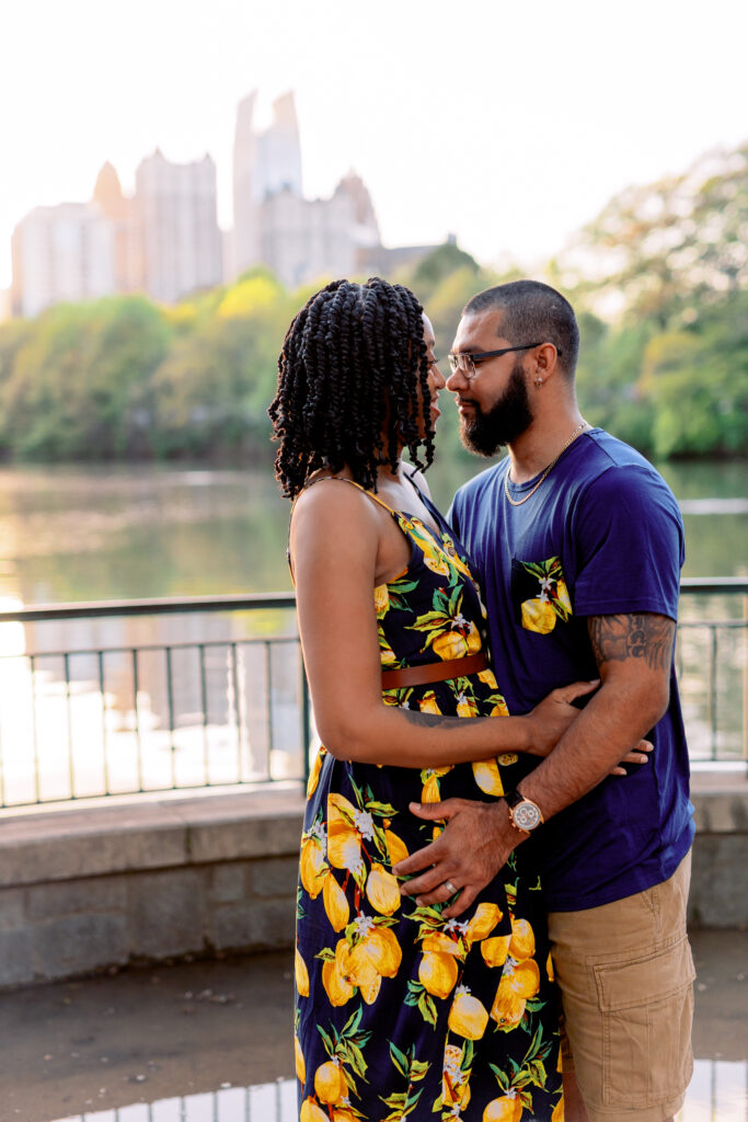 Couple smiles at each other at sunset in front of Atlanta Skyline at Piedmont Park