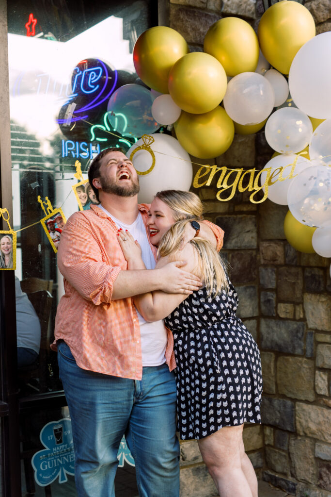 Newly engaged couple laughs after proposal at surprise engagement party Keegan's Public House in Kennesaw, Georgia