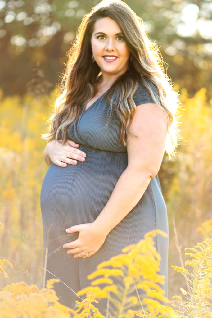 Beautiful pregnant mom smiles in sunlight at Green Meadows Preserve