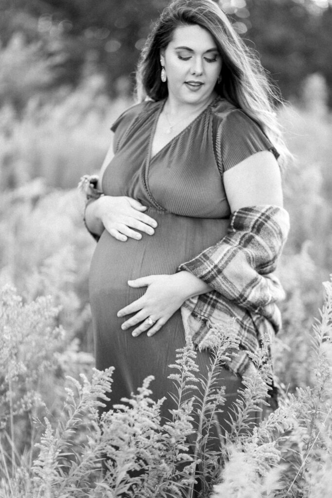 Beautiful pregnant mom holds belly in sunlight at Green Meadows Preserve