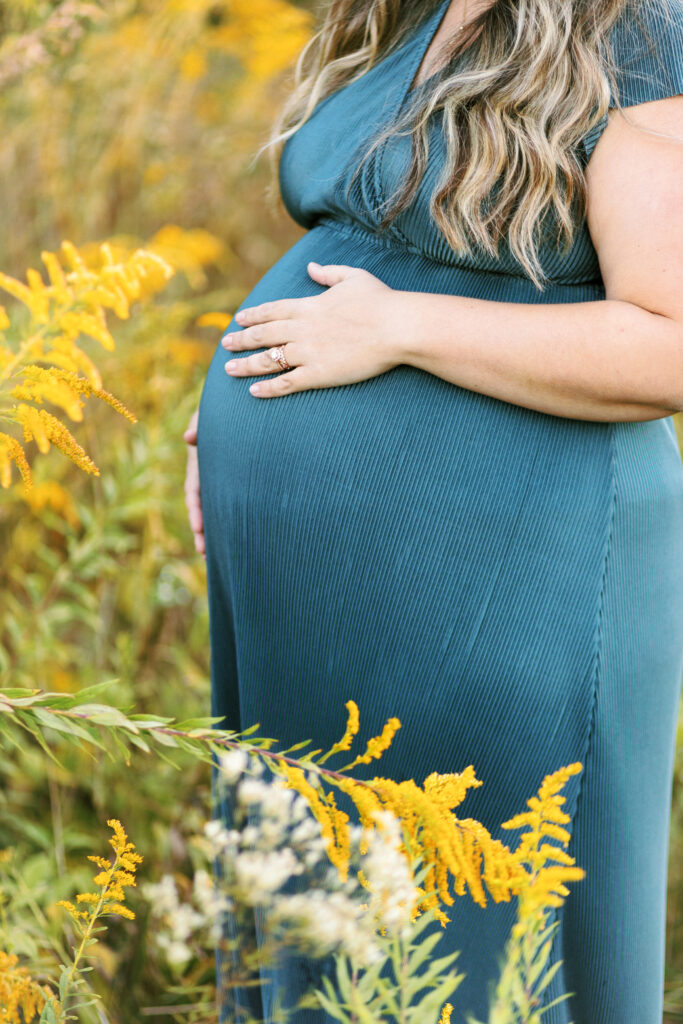 Pregnant baby bump in a field of yellow flowers during maternity photoshoot in Cobb County, Georgia