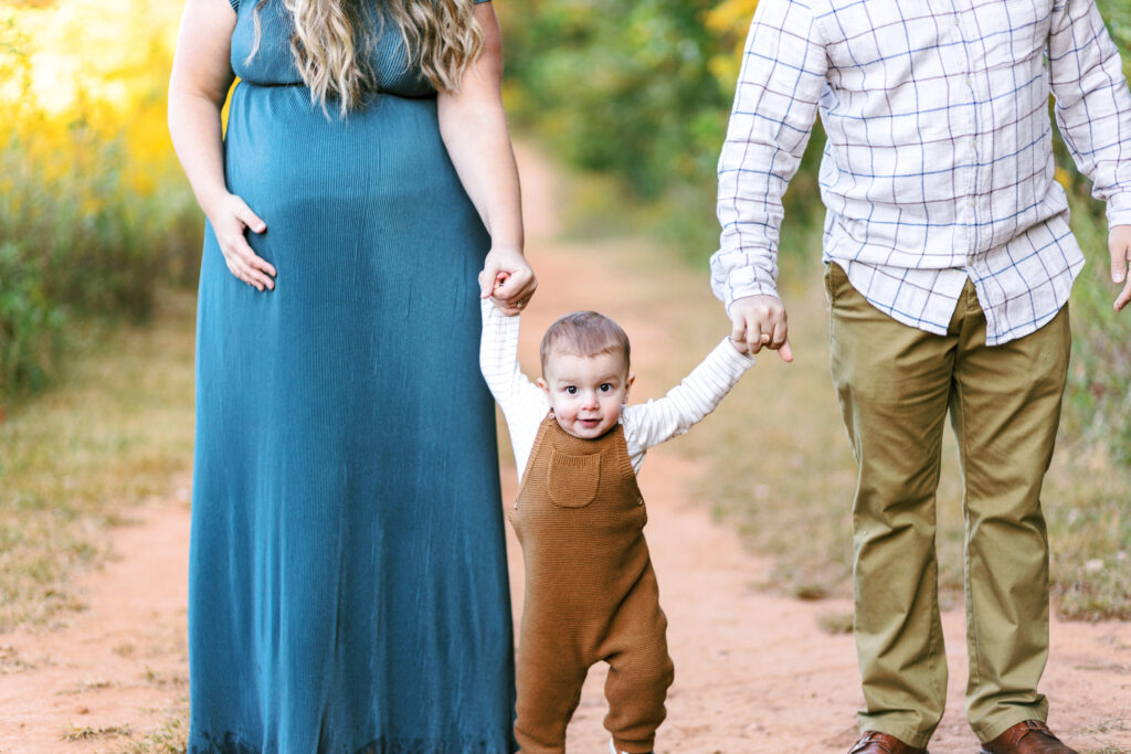 Family walks on path during motherhood photoshoot at Green Meadows Preserve in Marietta, Georgia