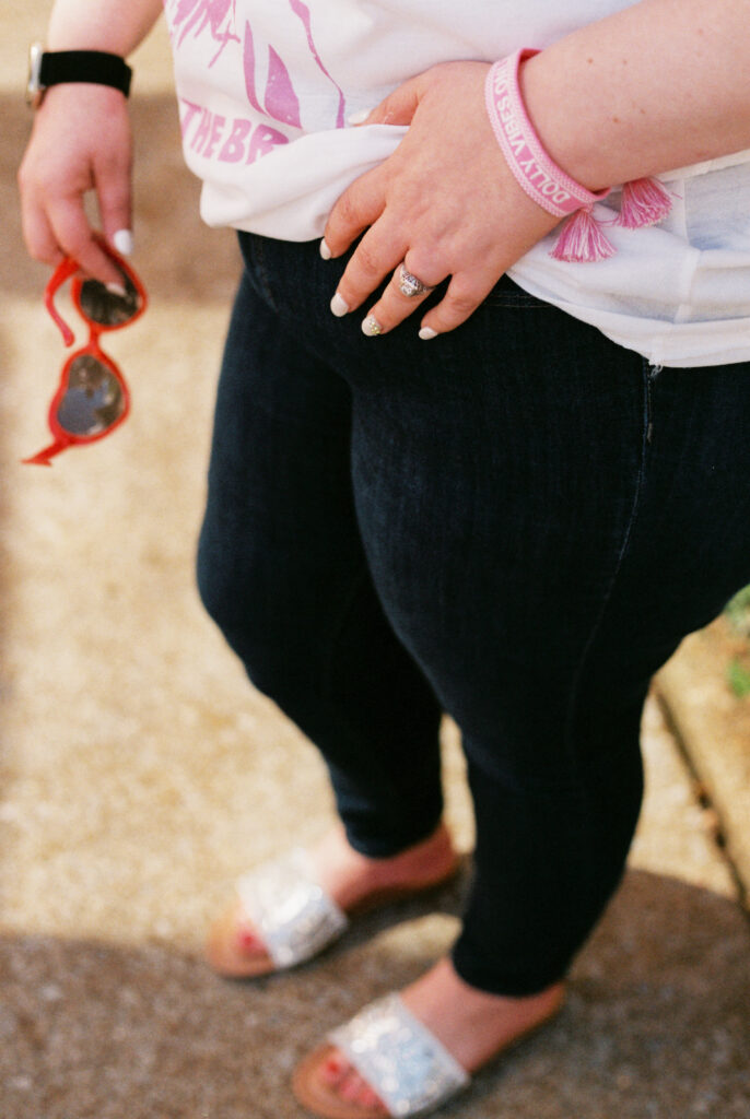 Dolly vibes only bracelet, heart-shaped sunglasses, sparking shoes, and an engagement ring on a Dolly Parton themed bachelorette party