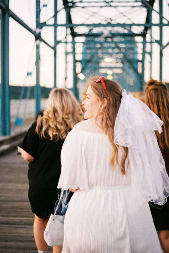 Bride and bridesmaids walk on Walnut Street Bridge in Chattanooga, TN